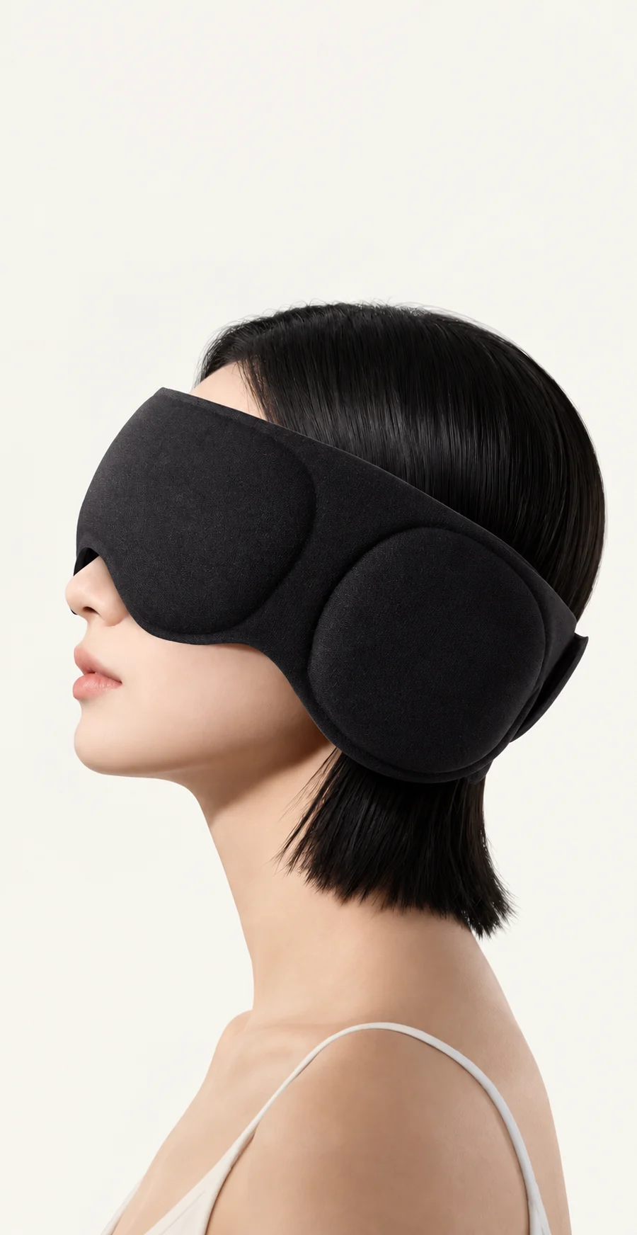 Side view of the black sleep mask showing its wide fabric band and padded ear cover