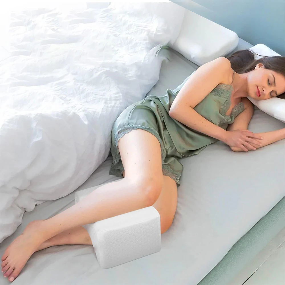 Person resting on their side with the white knee pillow between their legs